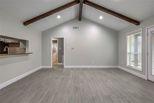 unfurnished living room with lofted ceiling with beams and light hardwood / wood-style floors