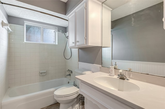 full bathroom featuring vanity, tiled shower / bath combo, a textured ceiling, and toilet