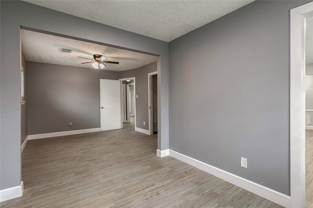 empty room featuring ceiling fan, a textured ceiling, and light wood-type flooring