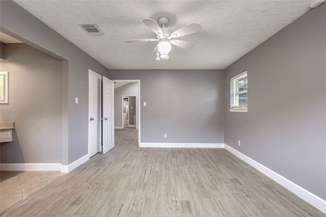 spare room with ceiling fan, a textured ceiling, and light wood-type flooring