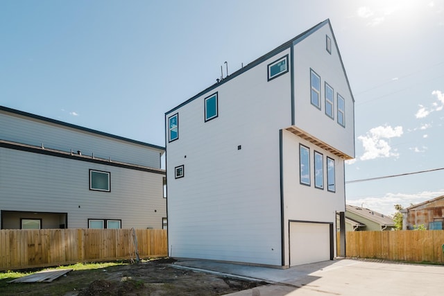 view of home's exterior with a garage, fence, concrete driveway, and stucco siding