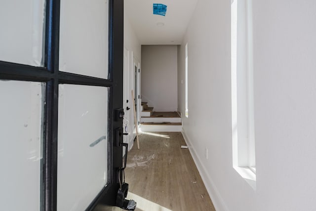 hall featuring stairway, baseboards, and wood finished floors