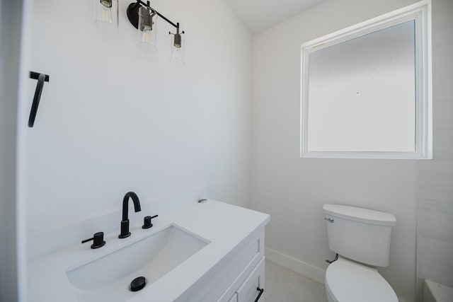 bathroom featuring toilet, baseboards, and vanity