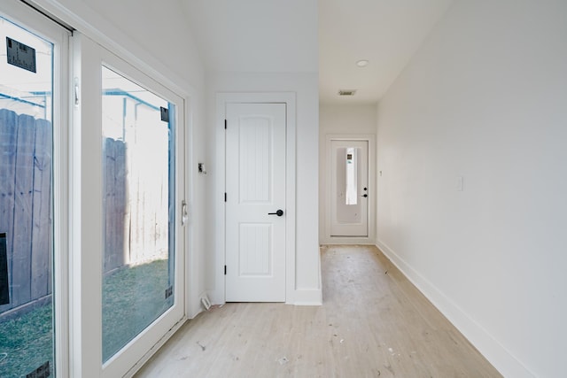 foyer entrance featuring light wood finished floors, plenty of natural light, visible vents, and baseboards