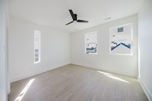 spare room with visible vents, light wood finished floors, a ceiling fan, and baseboards