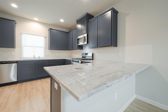 kitchen featuring light hardwood / wood-style flooring, gray cabinets, kitchen peninsula, and appliances with stainless steel finishes