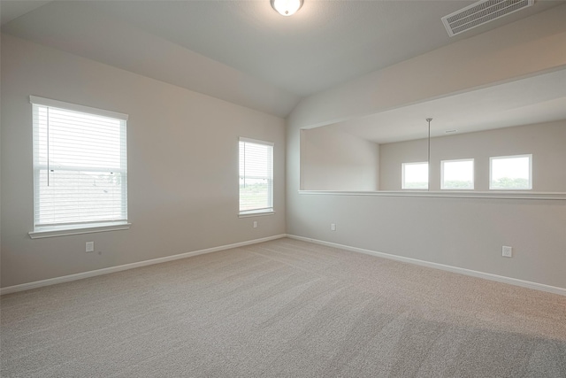 carpeted spare room featuring vaulted ceiling and a wealth of natural light