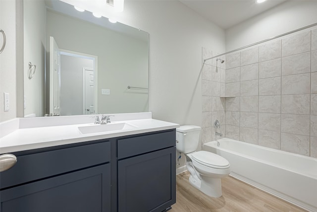 full bathroom featuring hardwood / wood-style flooring, tiled shower / bath, vanity, and toilet