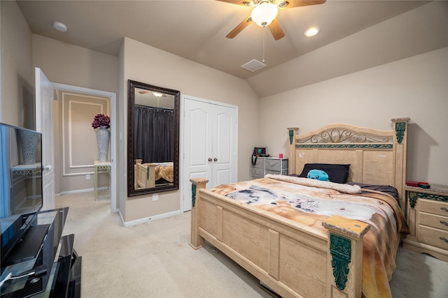 bedroom with vaulted ceiling, light colored carpet, ceiling fan, and a closet