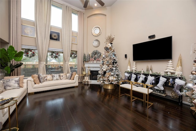 living room with ceiling fan, wood-type flooring, and a high ceiling