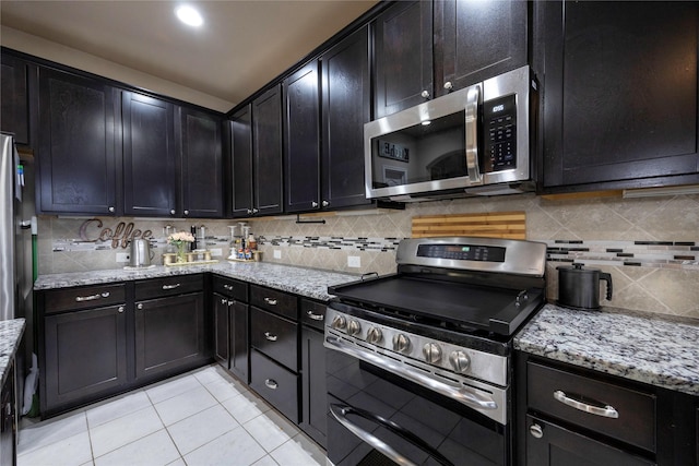 kitchen with tasteful backsplash, light stone counters, light tile patterned flooring, and appliances with stainless steel finishes