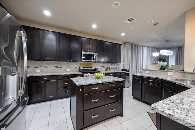 kitchen featuring pendant lighting, sink, appliances with stainless steel finishes, light stone countertops, and light tile patterned flooring