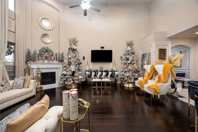 living room featuring ceiling fan, wood-type flooring, and a high ceiling