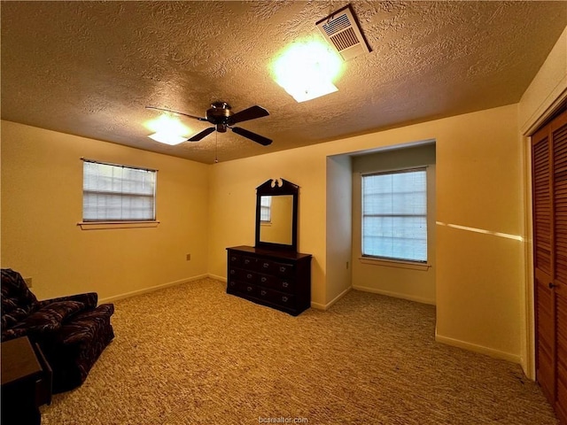 unfurnished room with ceiling fan, a textured ceiling, and carpet