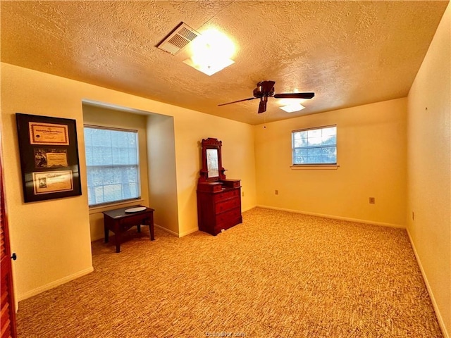 carpeted empty room with ceiling fan and a textured ceiling