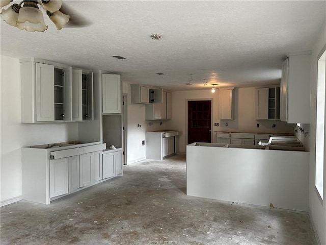 kitchen with white cabinetry, ceiling fan, and a textured ceiling