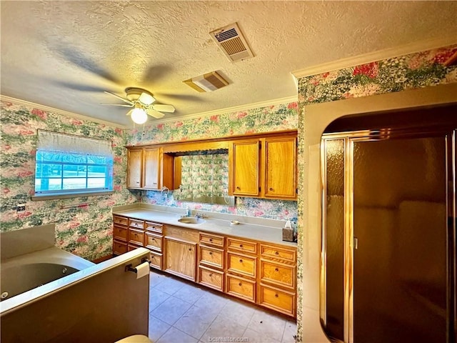 kitchen with light tile patterned floors, a textured ceiling, ornamental molding, and ceiling fan