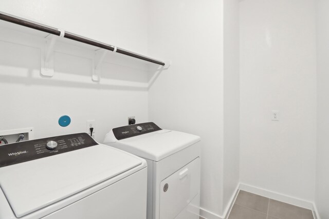 clothes washing area with washing machine and clothes dryer and tile patterned floors