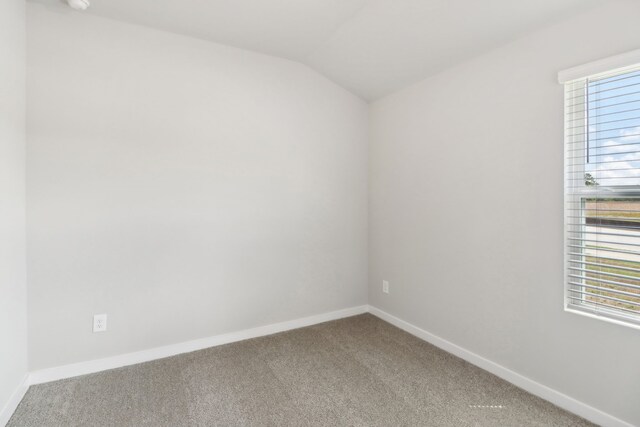 carpeted empty room with lofted ceiling