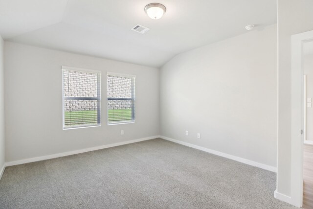 carpeted spare room with vaulted ceiling