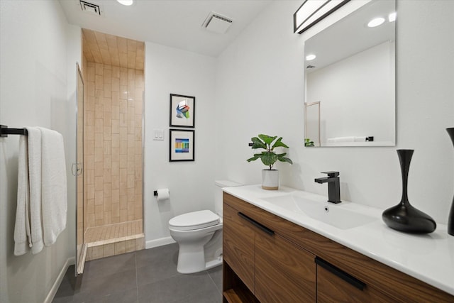 bathroom featuring tile patterned flooring, vanity, a tile shower, and toilet