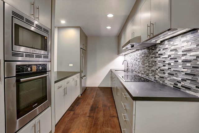 kitchen with dark wood-type flooring, stainless steel appliances, sink, and backsplash