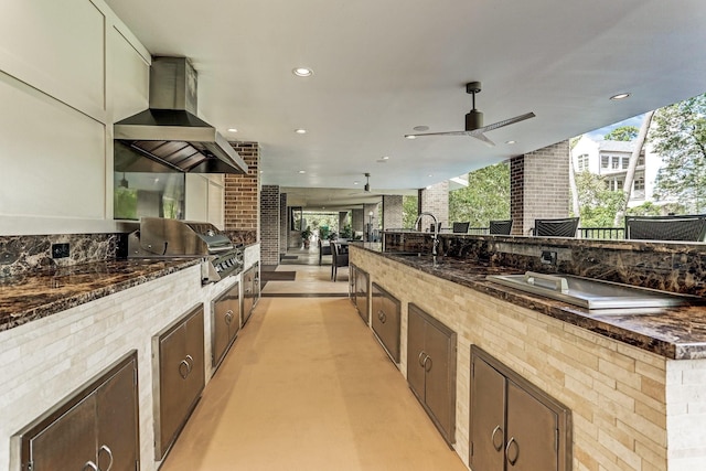 kitchen featuring island exhaust hood, dark stone counters, and sink