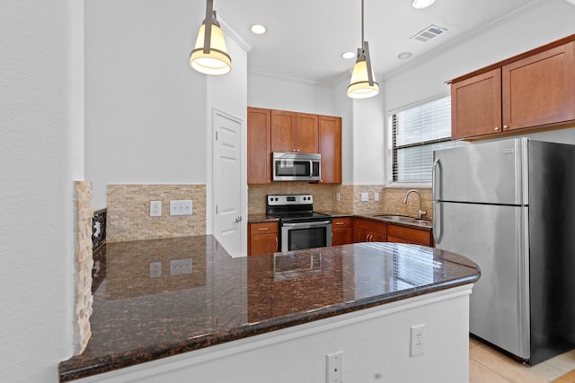 kitchen featuring a peninsula, a sink, visible vents, crown molding, and appliances with stainless steel finishes