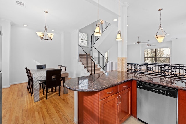 kitchen featuring dark stone counters, light wood-type flooring, visible vents, dishwasher, and decorative light fixtures