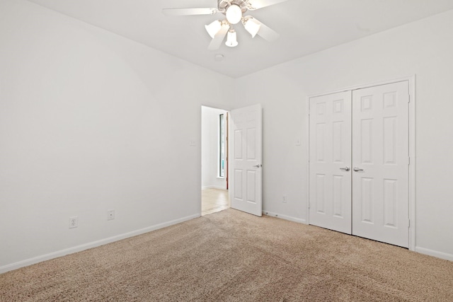 unfurnished bedroom featuring light carpet, baseboards, a closet, and ceiling fan