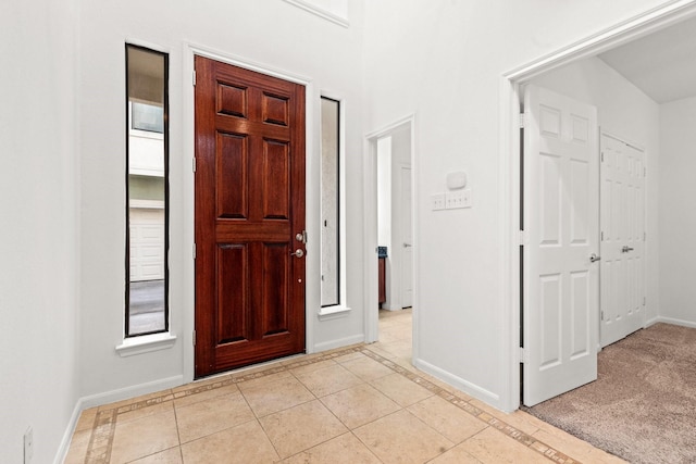 foyer featuring baseboards, a healthy amount of sunlight, and light tile patterned floors