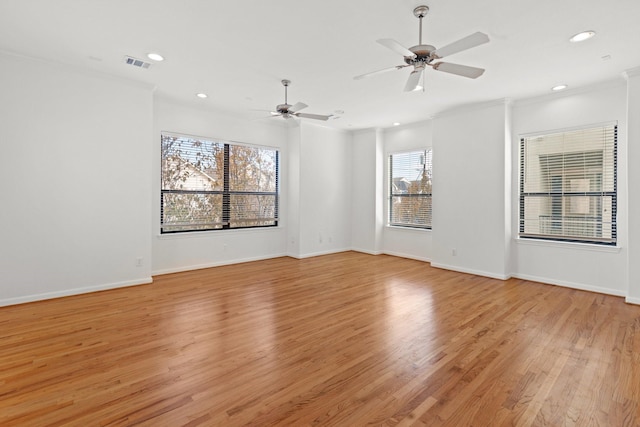 spare room with light wood-type flooring, visible vents, and crown molding