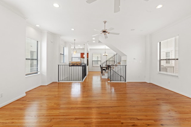 unfurnished living room with ceiling fan with notable chandelier, recessed lighting, and light wood finished floors