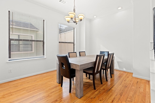 dining room featuring light wood-style flooring, baseboards, an inviting chandelier, and crown molding