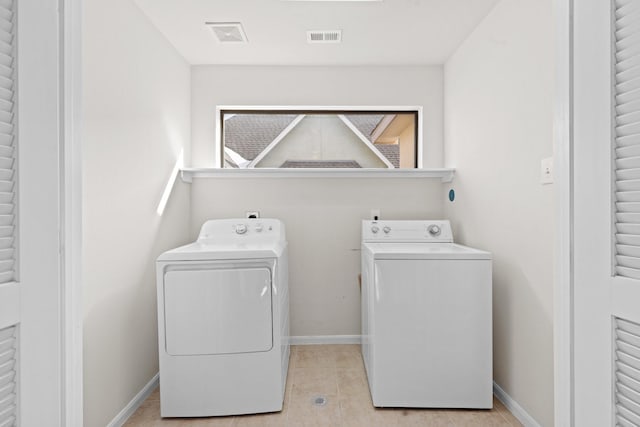 washroom featuring washing machine and dryer, visible vents, light tile patterned flooring, and laundry area