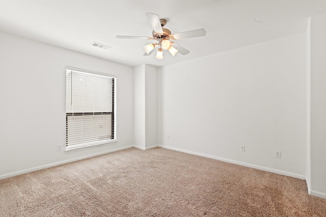 spare room with light carpet, a ceiling fan, visible vents, and baseboards