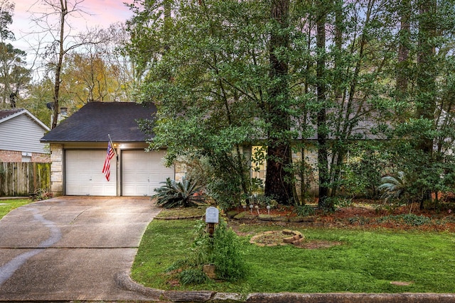 view of property hidden behind natural elements featuring a garage and a yard