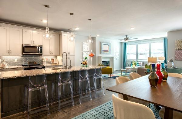 kitchen featuring sink, hanging light fixtures, light stone countertops, white cabinets, and a kitchen bar