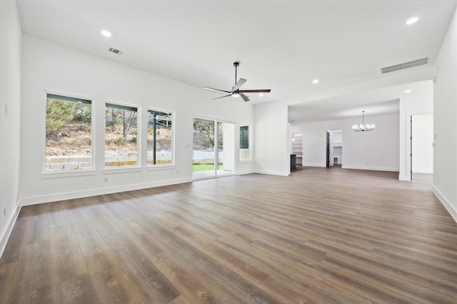 unfurnished living room with ceiling fan with notable chandelier, a wealth of natural light, and dark hardwood / wood-style floors