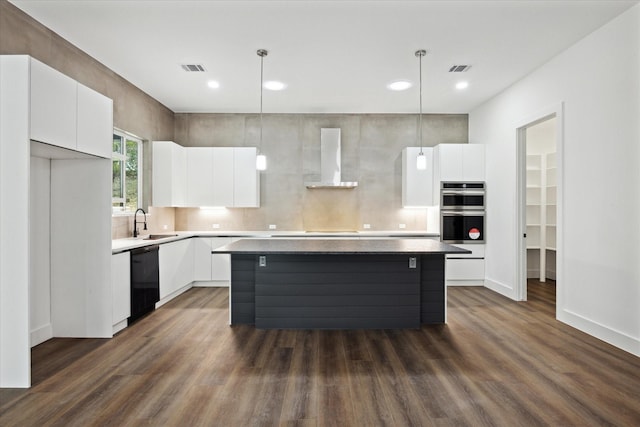 kitchen with white cabinetry, wall chimney exhaust hood, a kitchen island, and hanging light fixtures