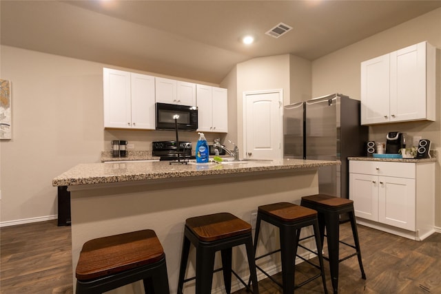 kitchen featuring an island with sink, electric range oven, white cabinets, and a kitchen breakfast bar