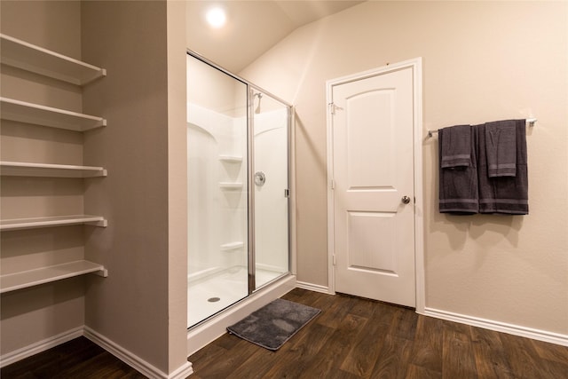 bathroom featuring lofted ceiling, hardwood / wood-style floors, and a shower with shower door