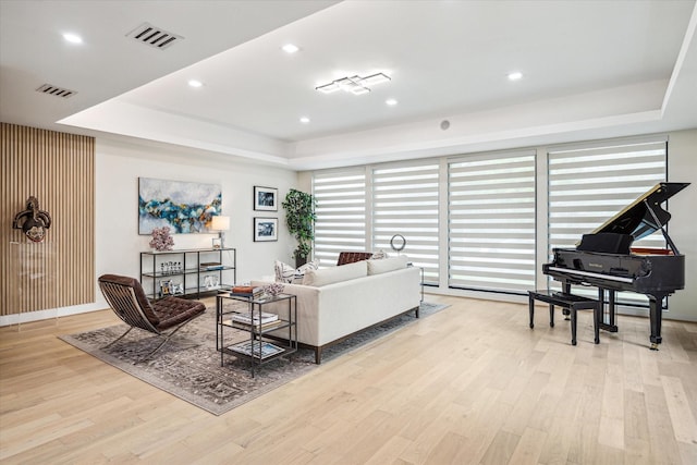 living room with light hardwood / wood-style flooring and a raised ceiling