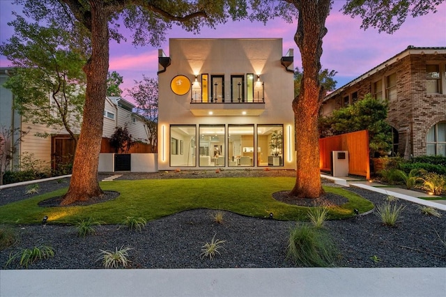 view of front of home featuring a yard and a balcony