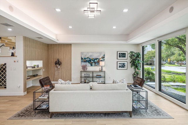 living room with a tray ceiling and light hardwood / wood-style flooring