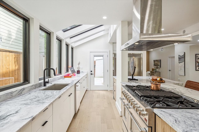 kitchen featuring sink, vaulted ceiling with beams, light stone counters, island range hood, and premium appliances