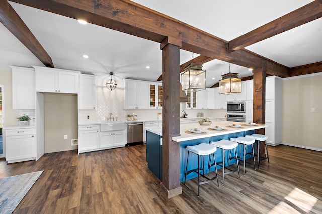 kitchen featuring dark wood-type flooring, stainless steel appliances, a center island, and white cabinets