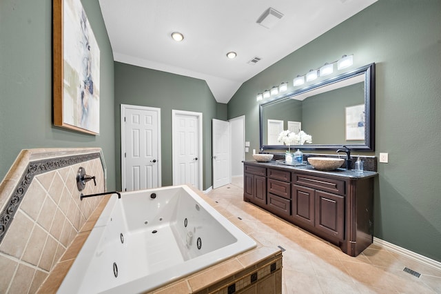 bathroom with a relaxing tiled tub, tile patterned floors, vaulted ceiling, and vanity