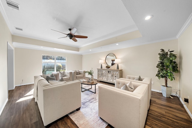 living room with dark wood-type flooring, ornamental molding, and a raised ceiling