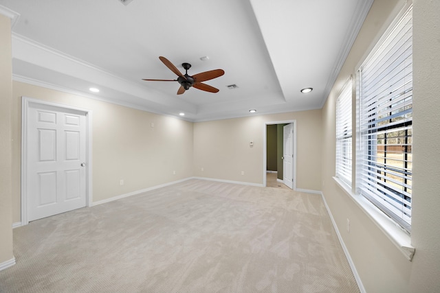 spare room featuring light carpet, a tray ceiling, ornamental molding, and ceiling fan